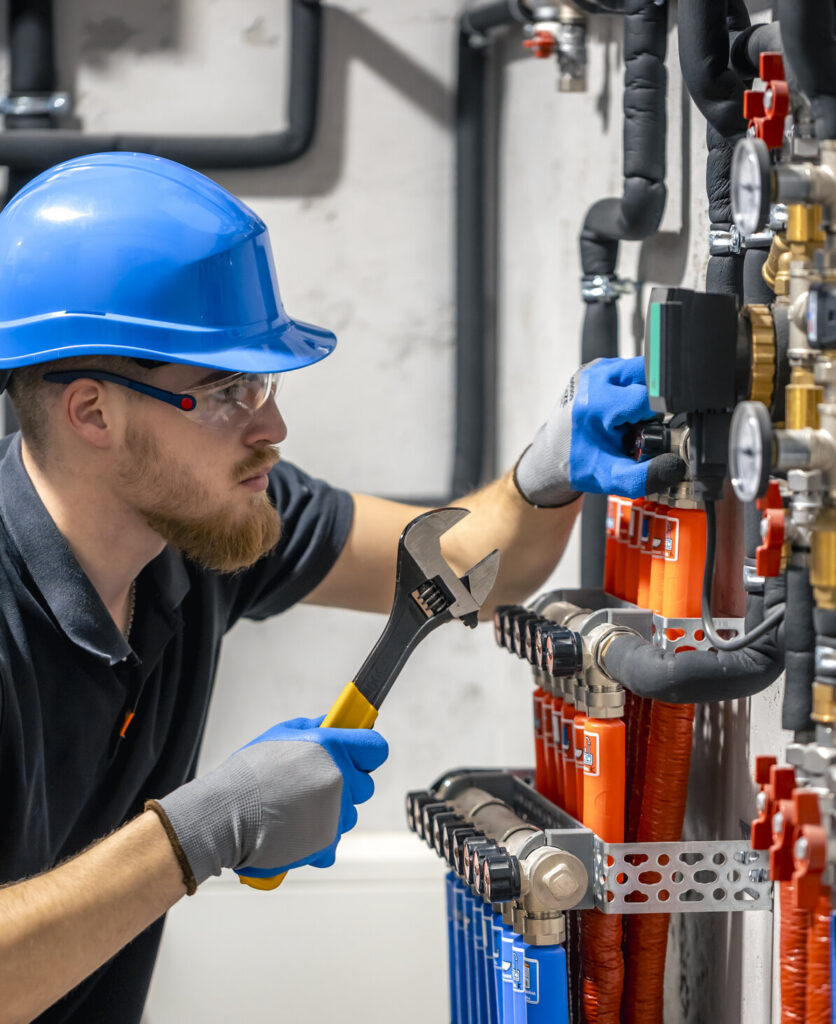 Técnico ajustando válvulas de circuito de água em casa de máquinas